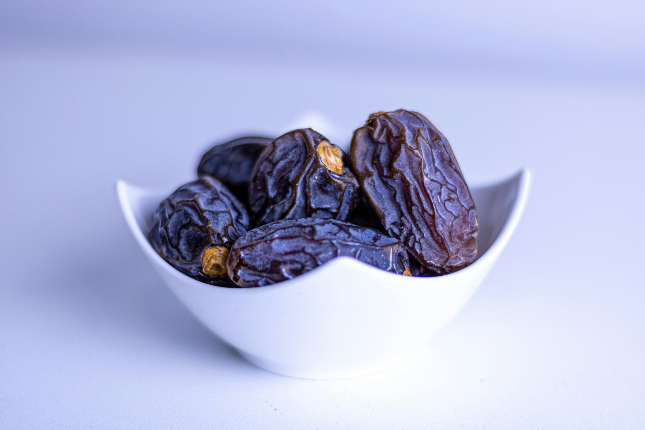 A close-up of fresh dates in a decorative white bowl, symbolizing Ramadan.